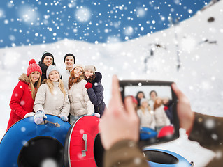 Image showing smiling friends with snow tubes and tablet pc