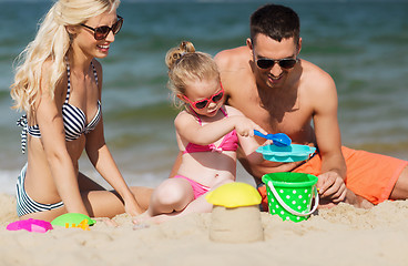 Image showing happy family playing with sand toys on beach