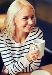 Image showing happy young woman drinking tea or coffee