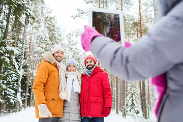 Image showing smiling friends with tablet pc in winter forest