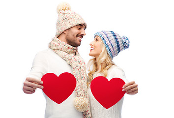 Image showing smiling couple in winter clothes with red hearts