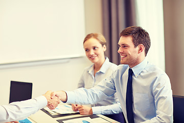 Image showing smiling business team shaking hands in office