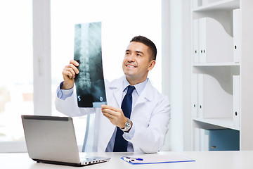 Image showing smiling male doctor in white coat looking at x-ray