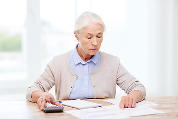 Image showing senior woman with papers and calculator at home