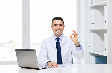 Image showing smiling doctor with laptop showing ok in office