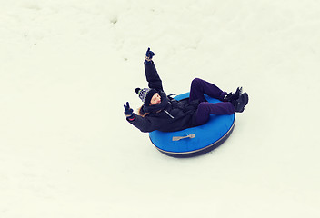 Image showing happy young man sliding down on snow tube