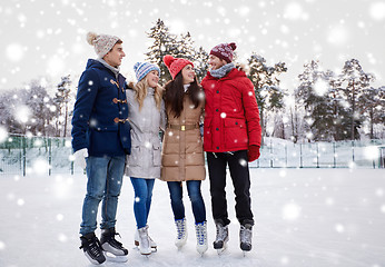 Image showing happy friends ice skating on rink outdoors