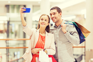 Image showing happy couple with smartphone taking selfie in mall