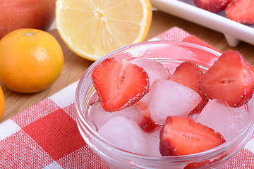 Image showing A slice of red strawberry on glass plate with lemon and mandarin in party theme background