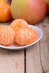 Image showing Bowls of slices mandarin with apple on rustic wooden background