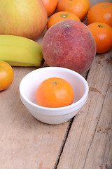 Image showing Mandarin Apples Bananas Peach on wooden plate