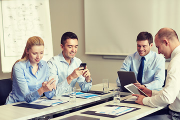 Image showing smiling business people with gadgets in office