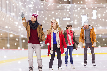 Image showing happy friends pointing finger on skating rink