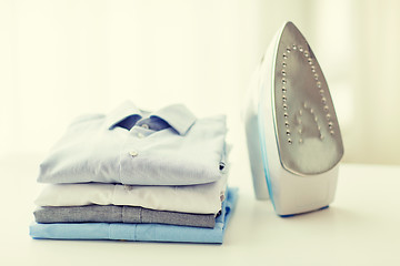 Image showing close up of iron and clothes on table at home