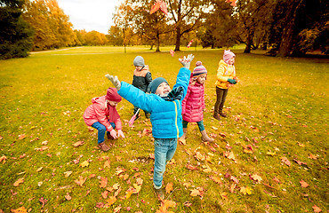 Image showing happy children playing with autumn leaves in park