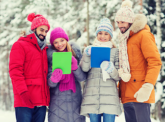 Image showing smiling friends with tablet pc in winter forest