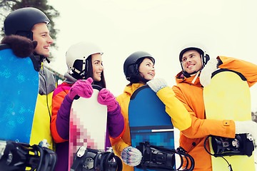 Image showing happy friends in helmets with snowboards talking
