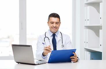 Image showing happy doctor with clipboard and laptop in office