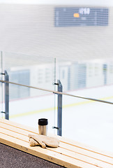 Image showing thermos cup and mittens on bench at ice rink arena