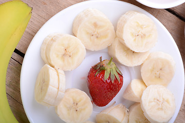 Image showing healthy strawberry and bananas slices on wooden background