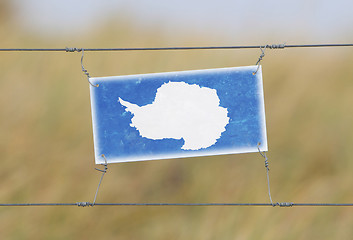 Image showing Border fence - Old plastic sign with a flag