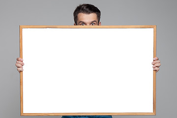 Image showing The surprised man showing empty white billboard or banner on gray background