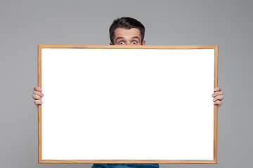 Image showing The surprised man showing empty white billboard or banner on gray background