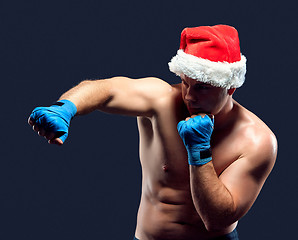 Image showing Christmas fitness boxer wearing santa hat boxing on black 