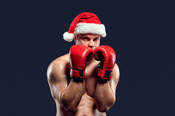 Image showing Christmas fitness boxer wearing santa hat boxing on black background