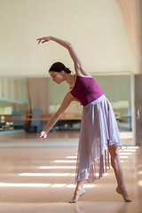 Image showing classic ballet dancer posing at barre on rehearsal room background