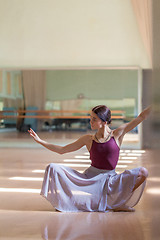 Image showing classic ballet dancer posing at barre on rehearsal room background