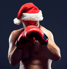 Image showing Christmas fitness boxer wearing santa hat boxing on black background