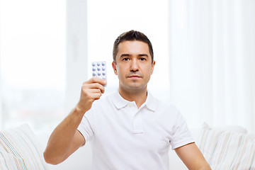 Image showing man showing pack of pills at home