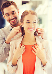 Image showing couple trying golden pendant on at jewelry store