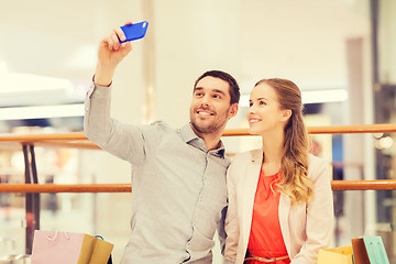 Image showing happy couple with smartphone taking selfie in mall