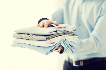 Image showing close up of businessman holding folded shirts