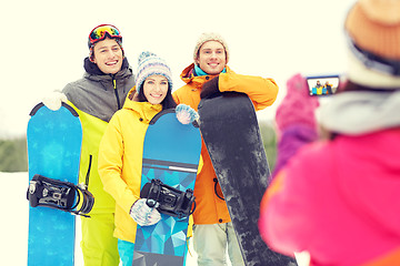 Image showing happy friends with snowboards and smartphone