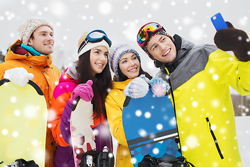 Image showing happy friends with snowboards and smartphone