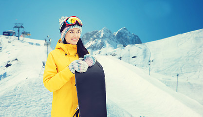 Image showing happy young woman with snowboard over mountains