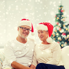 Image showing happy senior couple in santa helper hats at home