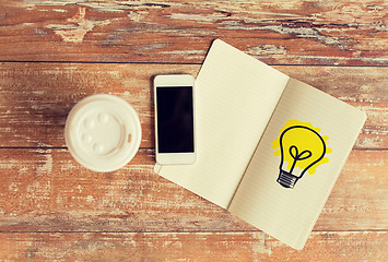 Image showing close up of notebook, coffee cup and smartphone