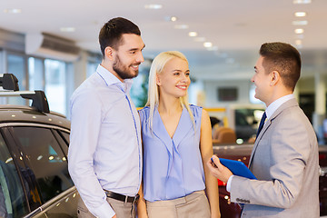 Image showing happy couple with car dealer in auto show or salon