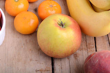 Image showing Mandarin Apples Bananas Peach on wooden plate