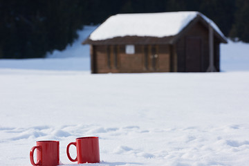 Image showing two red coups of hot tea drink in snow  at winter