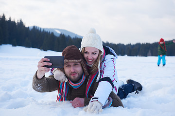 Image showing romantic couple have fun in fresh snow and taking selfie