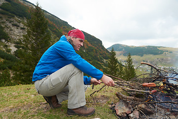 Image showing hiking man prepare tasty sausages on campfire