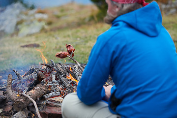 Image showing hiking man prepare tasty sausages on campfire