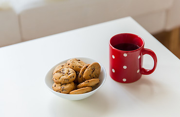 Image showing close up of oat cookies and red tea cup on table