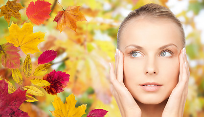 Image showing beautiful woman touching her face over autumn