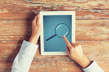 Image showing close up of male hands with magnifier on tablet pc